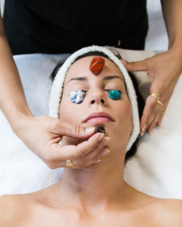 Beautiful young woman receiving gemstone therapy in spa.